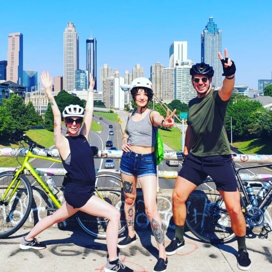 3 bike riders pose on a bridge in Atlanta, Georgia