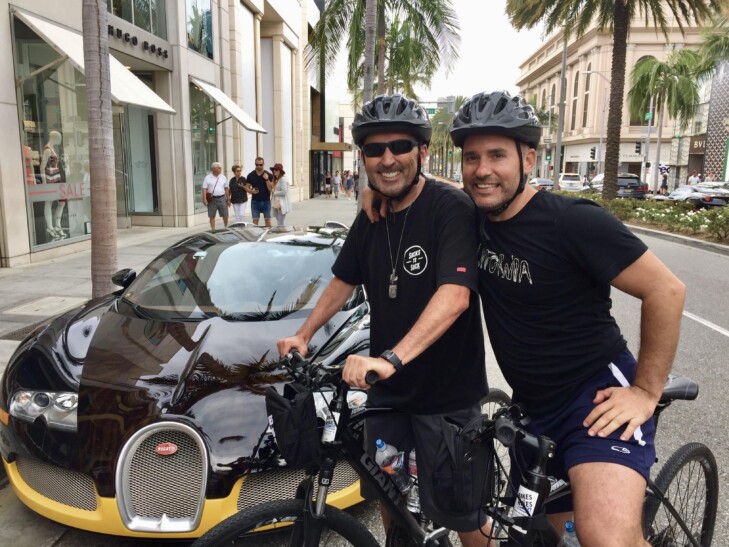 Cyclists pose beside a luxury car in Los Angeles, California