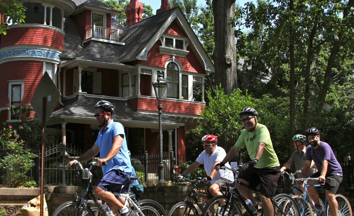 Cyclists ride through Inman Park in front of historic houses in Atlanta, Georgia