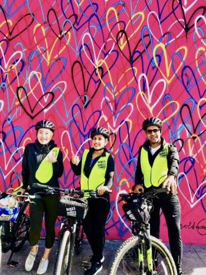 Guests pose in front of a pink wall with hearts on it in Los Angeles, California