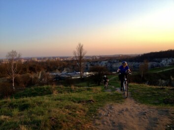 A woman on a bike riding through the countryside outside Krakow as the sun is setting