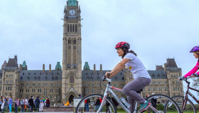 Cyclists ride in front of the Parliament Building in Ottawa, Canada