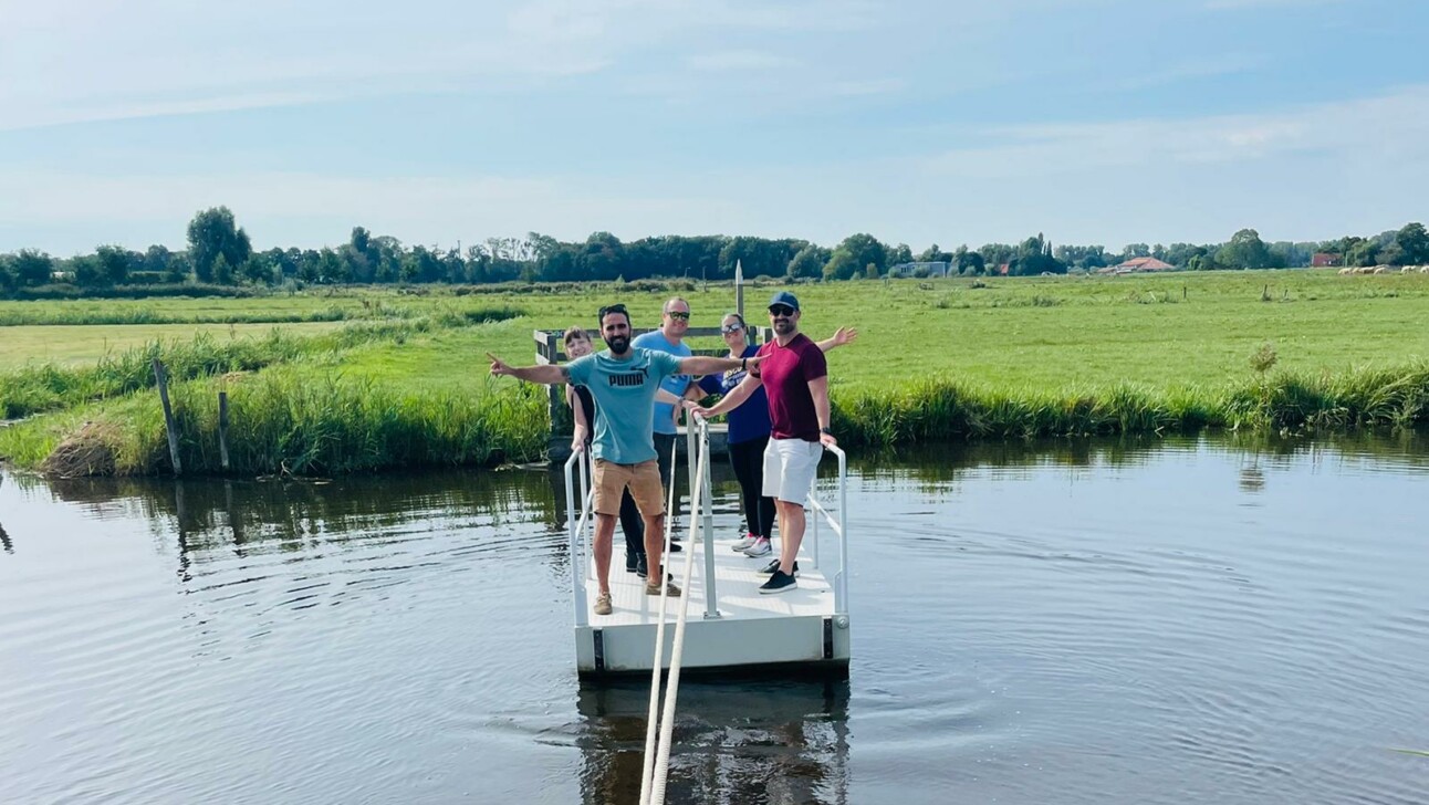 A group of people standing on a small pontoon on a lake outside Amsterdam